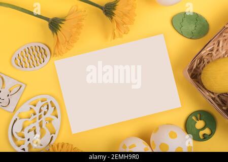 Flat lay with painted easter eggs, gerbera flower and easter decorations on yellow background. copy space Stock Photo