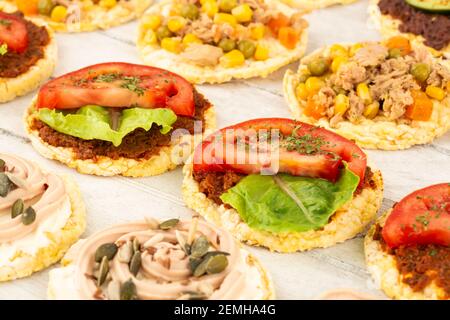 Quinoa crackers with olive and sundried tomatoes paste, tuna fish and vegetables on gray wooden background. Stock Photo