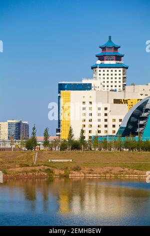 Kazakhstan, Astana, View of city skyline looking towards the House of Ministries and The Beijing Palace Soluxe Hotel  reflecting in Ishim River Stock Photo