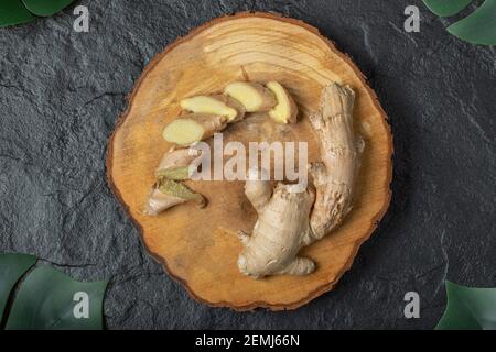 Sliced ginger roots on wooden piece Stock Photo