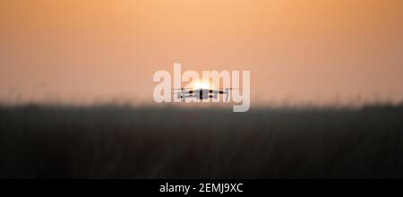 Drone quadcopter with digital camera in flight at sunset, Silhouette of drone at sunset Stock Photo