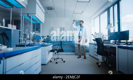Modern Medical Research Laboratory with Male Scientist Analysing Microbiological Sample, Using Microscope. Advanced Scientific Lab for Drugs, Vaccine Stock Photo