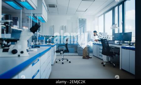 Modern Medical Research Laboratory with Male Scientist Looking Under Microscope, Analysing Microbiological Sample. Advanced Scientific Lab for Drugs Stock Photo