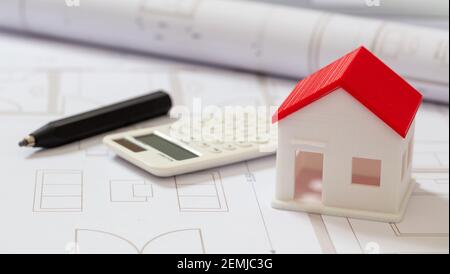 Calculator and architectural house model on blueprint plans background. Construction budget concept. Stock Photo