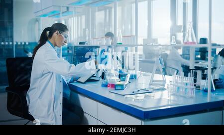 Modern Medical Research Laboratory: Female Scientists Working with Pipette, Using Digital Tablet, Analysing Biochemicals Samples. Scientific Medicine Stock Photo