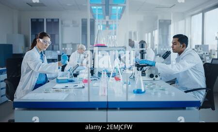 Modern Medical Research Laboratory: Diverse Team of Scientists Working with Pipette, Analysing Biochemicals Samples, Talking. Scientific Lab for Stock Photo