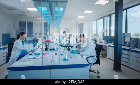 Modern Medical Research Laboratory: Diverse Team of Scientists Working Using Microscope, Analysing Microbiology Samples. Scientific Lab for Medicine Stock Photo