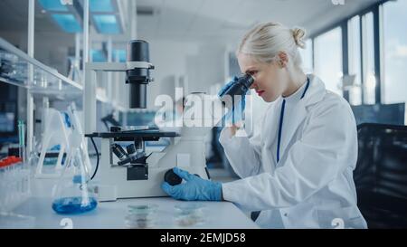 Modern Medical Research Laboratory: Portrait of Female Scientist Looking Under Microscope, Analysing Biochemicals Samples. Advanced Scientific Lab for Stock Photo