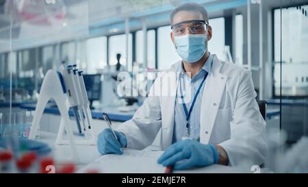 Medical Research Laboratory: Portrait of Male Scientist Wearing Face Mask Looking at Camera, Writing Down Information. Advanced Scientific Lab for Stock Photo