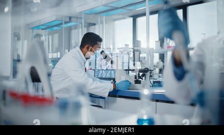 Medical Research Laboratory: Male Scientist Looking Under Micrsocope, Analyzing Samples. Advanced Scientific Lab Biotechnology, Medicine Development Stock Photo