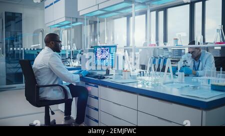 Modern Medical Laboratory: Male Scientist, Typing on Keyboard working on Computer, Scren Shows DNA Research Concept. Advanced Scientific Lab, Medicine Stock Photo