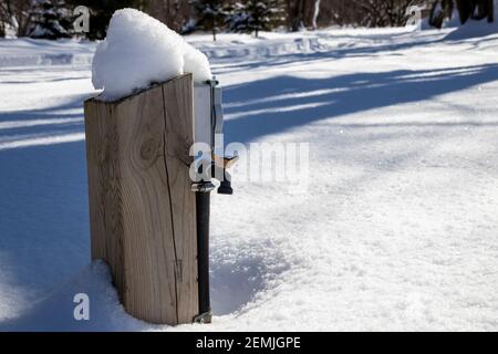 A water and electric hookup covered by snow during winter season on a closed campsite; water pump foutain Stock Photo