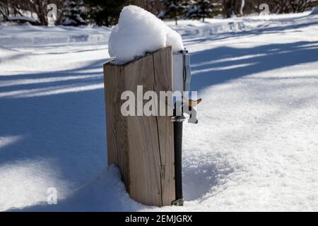 A water and electric hookup covered by snow during winter season on a closed campsite, water pump foutain Stock Photo