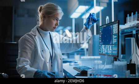 Medical Research Laboratory: Portrait of Female Scientist Working on Computer, Analysing Liquid Sample in a Labolatory Flask. Advanced Scientific Lab Stock Photo