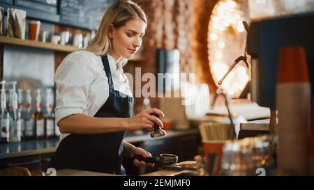 Beautiful Young Caucasian Barista with Blond Hair is Making a Cup of Fresh Coffee in a Cafe. Happy and Smiling Bar Employee Posing while Working in a Stock Photo