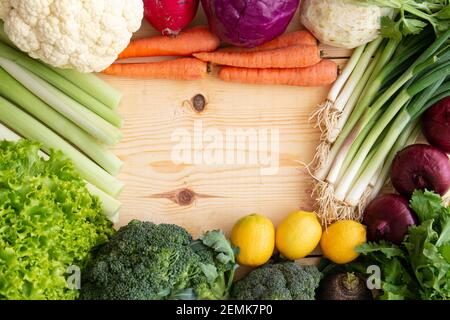 On the wood are carrots, broccoli, lettuce, cauliflower, radish, spring onion, leek, lemon, celery. space in the wood for writing. Stock Photo