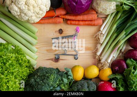 Various vegetables and tiny market car on wood. Buying healthy vegetables from the market. Stock Photo