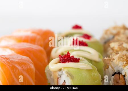 Sushi rolls with avocado and tobiko caviar and philadelphia rolls. Macro. Photo can be used as a whole background. Stock Photo