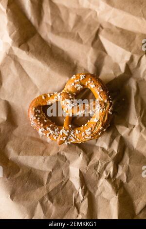 Hard Twisted Pretzel with Salt Against Brown Paper Background Stock Photo