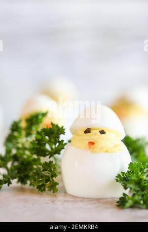 Deviled eggs for Easter decorated as cute little chicks hatching from eggs with carrot beak and seaweed eyes. Extreme shallow depth of field with blur Stock Photo