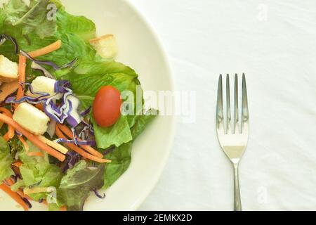 fresh vegetable salad topping crispy bread dressing on plate with silver fork Stock Photo