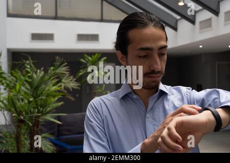 long haired business man looking at his smart watch. heart meter. man interacting with smart watch. life style. Stock Photo