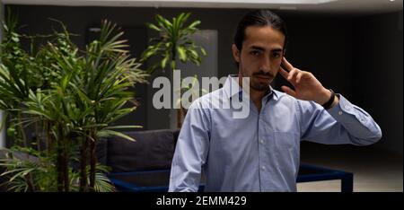 serious businessman holding wireless headset to receive a call. panoramic photo. elegant man in his home office. Stock Photo