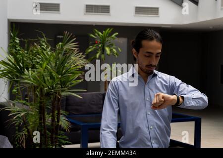 young businessman in a corporate space. home office. checking his smart and touch watch. Stock Photo