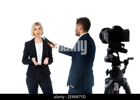 anchorman with hand in pocket taking interview form blonde businesswoman isolated on white, blurred foreground Stock Photo