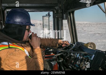 Indigenous male truck driver working during winter construction of Inuvik-Tuktoyaktuk Highway, Northwest Territories, Canada's western Arctic. Stock Photo