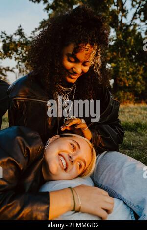 Young woman resting head on female friend's lap in park Stock Photo