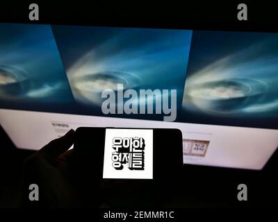 Person holding mobile phone with logo of South Korean software company Woowa Brothers Corp. on screen in front of web page. Focus on phone display. Stock Photo
