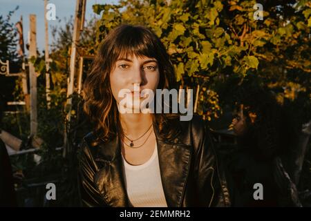 Portrait of young woman against plants in park Stock Photo