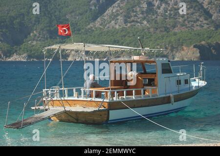 Boat with Turkish flag on sea with mountains in the background. Stock Photo