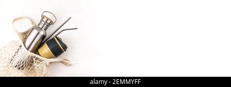Banner made from mesh bag with reusable metal water bottle and cup on white wooden background. Stock Photo