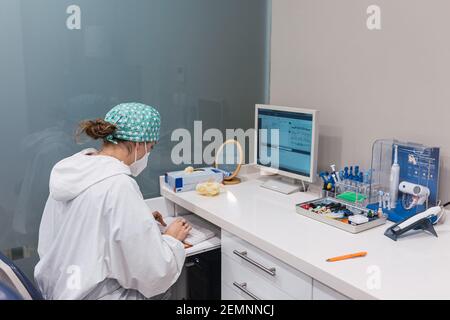 Female dentist using computer at office desk. Looking at the screen Stock Photo