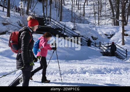 Montreal, CA - 2 February 2021: Two women walking on a snowy trail in Montreal's Mount Royal Park (Parc Du Mont-Royal) after snow storm. Stock Photo
