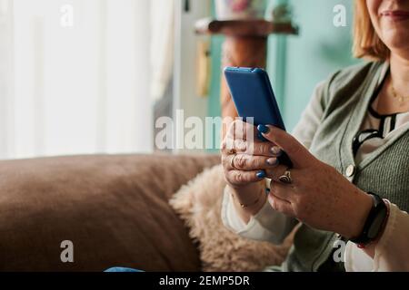 Close-up of a middle-aged woman looks at her phone at home Stock Photo
