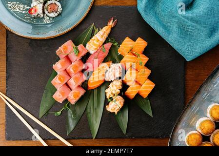Sushi and soy sauce in a bowl and wooden chopsticks on a gray wooden table. Japanese food. Sushi Set. Variety of rolls. Menu. Stock Photo