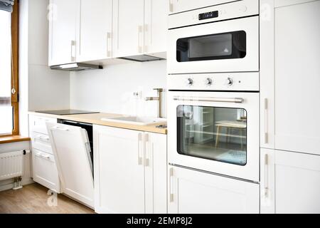 Modern Scandinavian-Style kitchen or living room, minimalist interior design, oven, microwave and sink with wooden board, electric stove Stock Photo