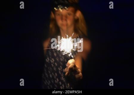 Girl holding a bright sparkler in her hand Stock Photo