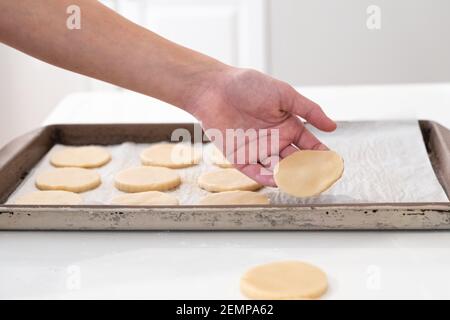 A person placing cut pieces of cookie dough on an oven tray. Stock Photo