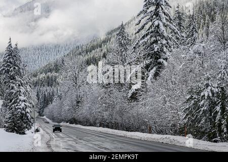 Traffic on US 2 in Washington State after a snow storm travels through a snowy wonderland below Stevens Pass in winter Stock Photo