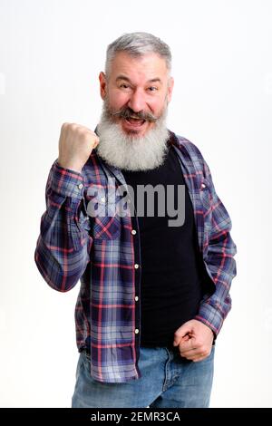 Studio portrait of mature bearded man in casual clothes raised his hand up, gesture of victory and joy, yes sign, white background Stock Photo