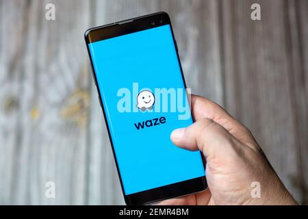 A mobile phone or cell phone being held by a hand with the Waze app open on screen Stock Photo