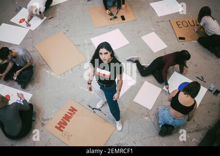 High angle portrait of woman standing while male and female activist preparing signboards in building Stock Photo