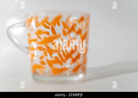 a single glass cup with a orange pattern on a white background Stock Photo
