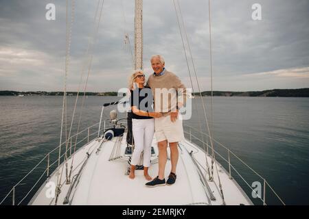 Senior woman looking at man while standing on boat against sky during sunset Stock Photo