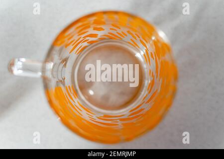 a single glass cup with a orange pattern on a white background from above Stock Photo