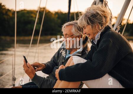 Smiling heterosexual couple using smart phone during sunset Stock Photo